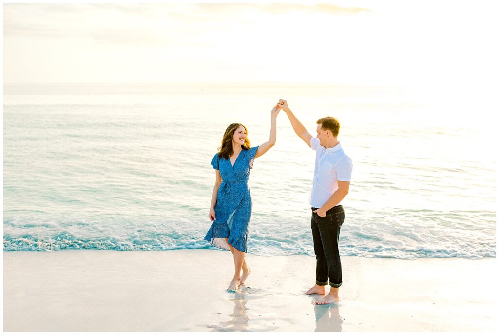 couple dancing on beach in florida for engagement photos with women in blue dress