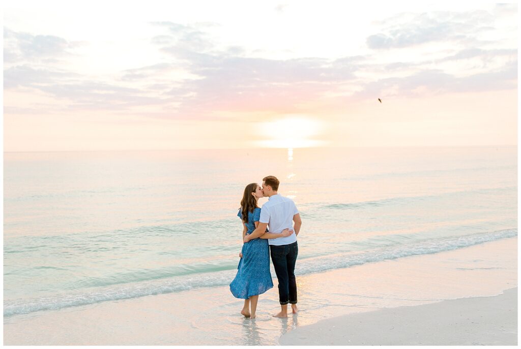 couple kissing at sunset on florida beach for engagement photos